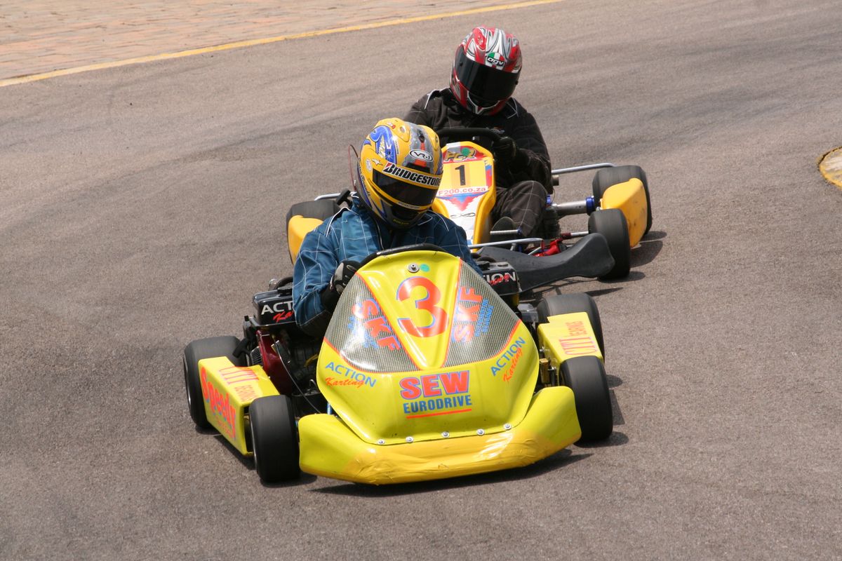 Deux pilotes de karting en course sur une piste extérieure