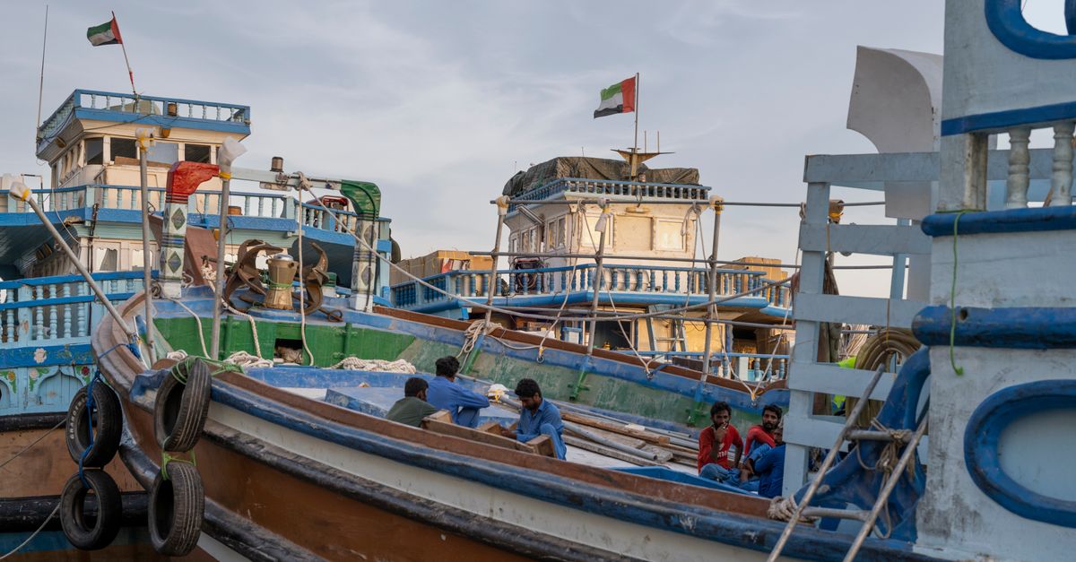 Colorful traditional boats at Dubai harbor with flags, showcasing cultural maritime life.