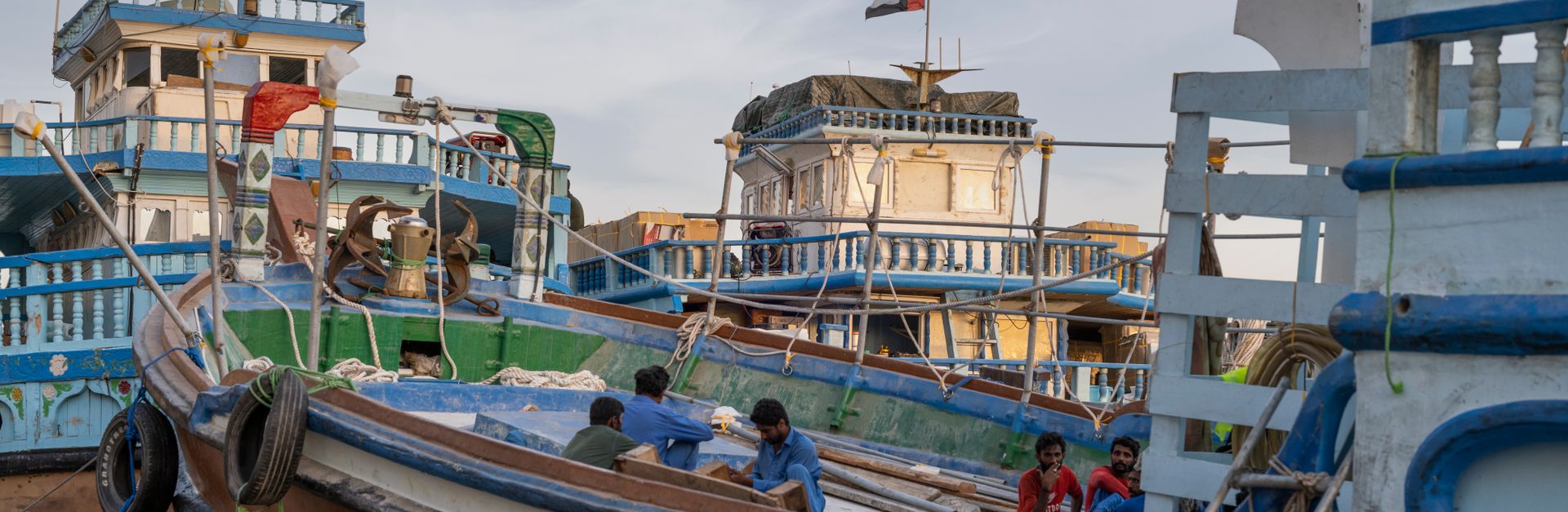 Colorful traditional boats at Dubai harbor with flags, showcasing cultural maritime life.