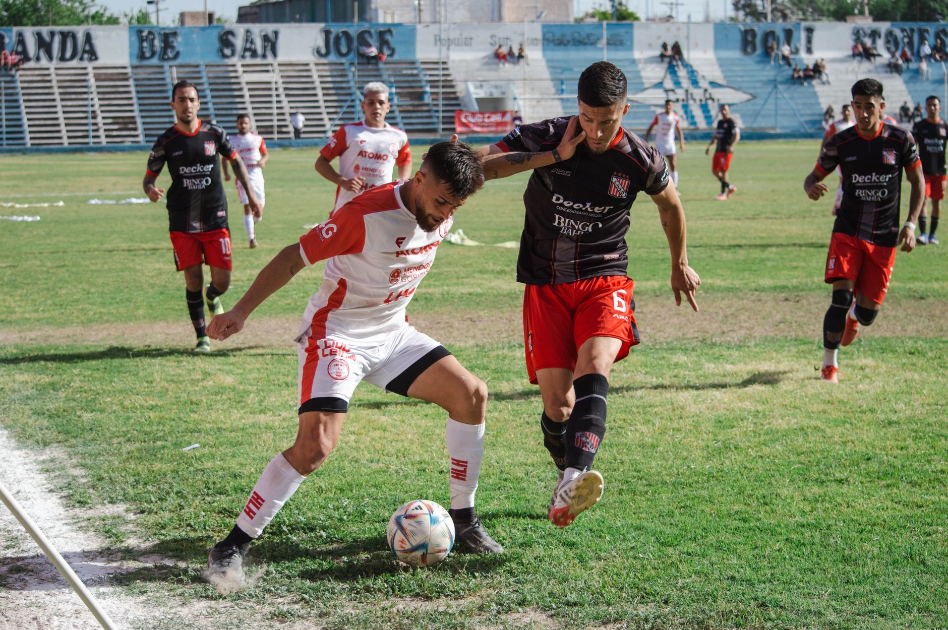 Competitive soccer match with players in action at an outdoor football field.