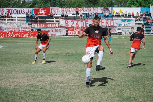 Soccer players practicing on a sunny day at a local field with vibrant background banners.