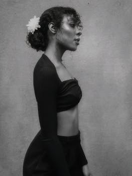 Stylish black and white portrait of a woman in a crop top with a flower in hair.