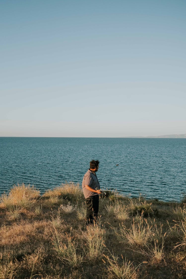 Man Standing On Coastal Cliff Overlooking  Ocean View