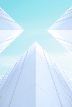 Low-angle view of symmetrical modern white buildings against a bright blue sky.