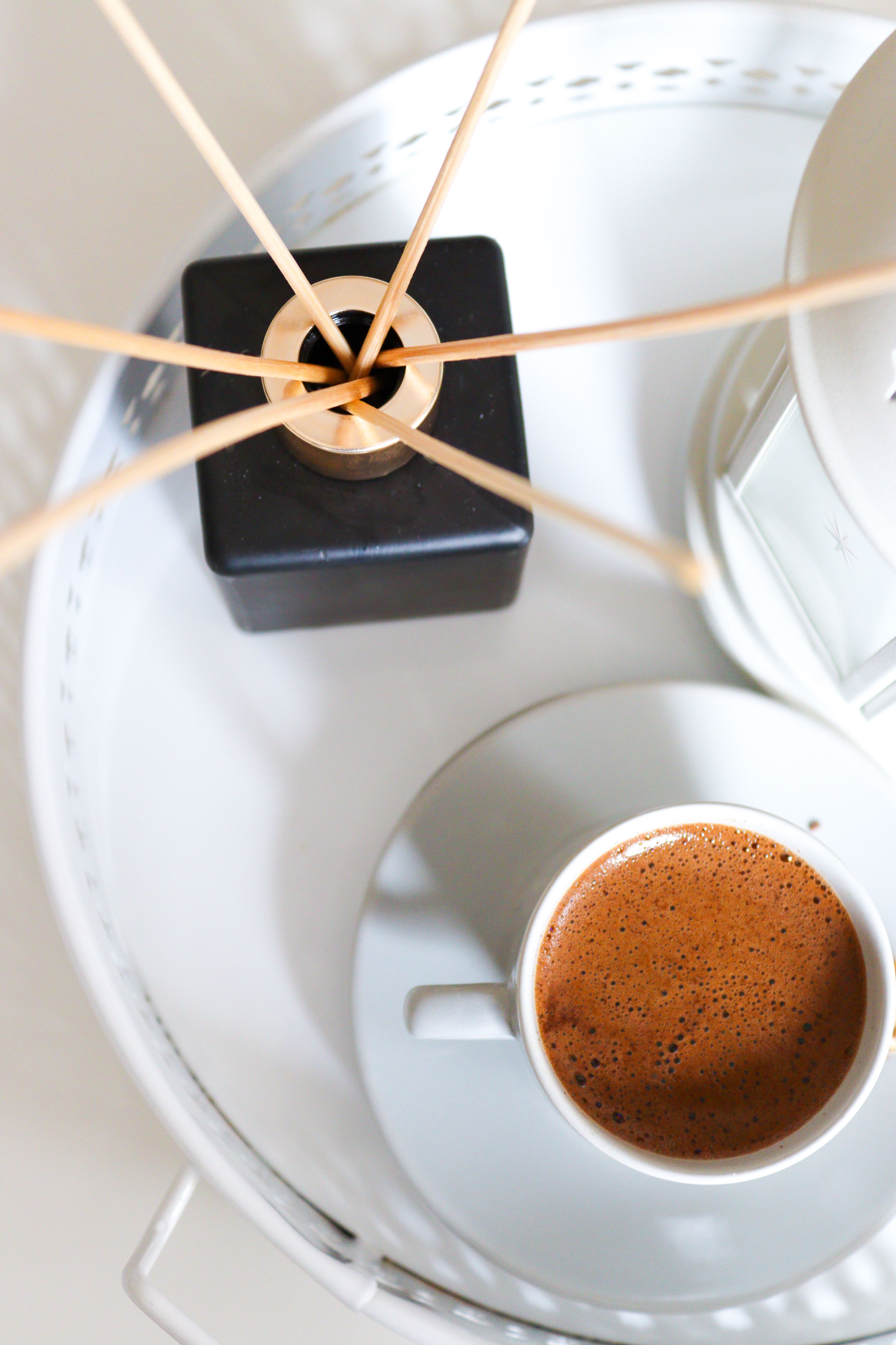 Small ceramic vase filled with wooden coffee stir sticks on a coffee bar hutch