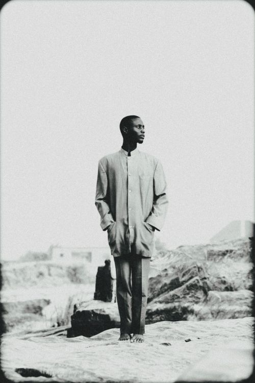 Free Artistic black and white photo of a man posing in a desert landscape, blending fashion and nature. Stock Photo