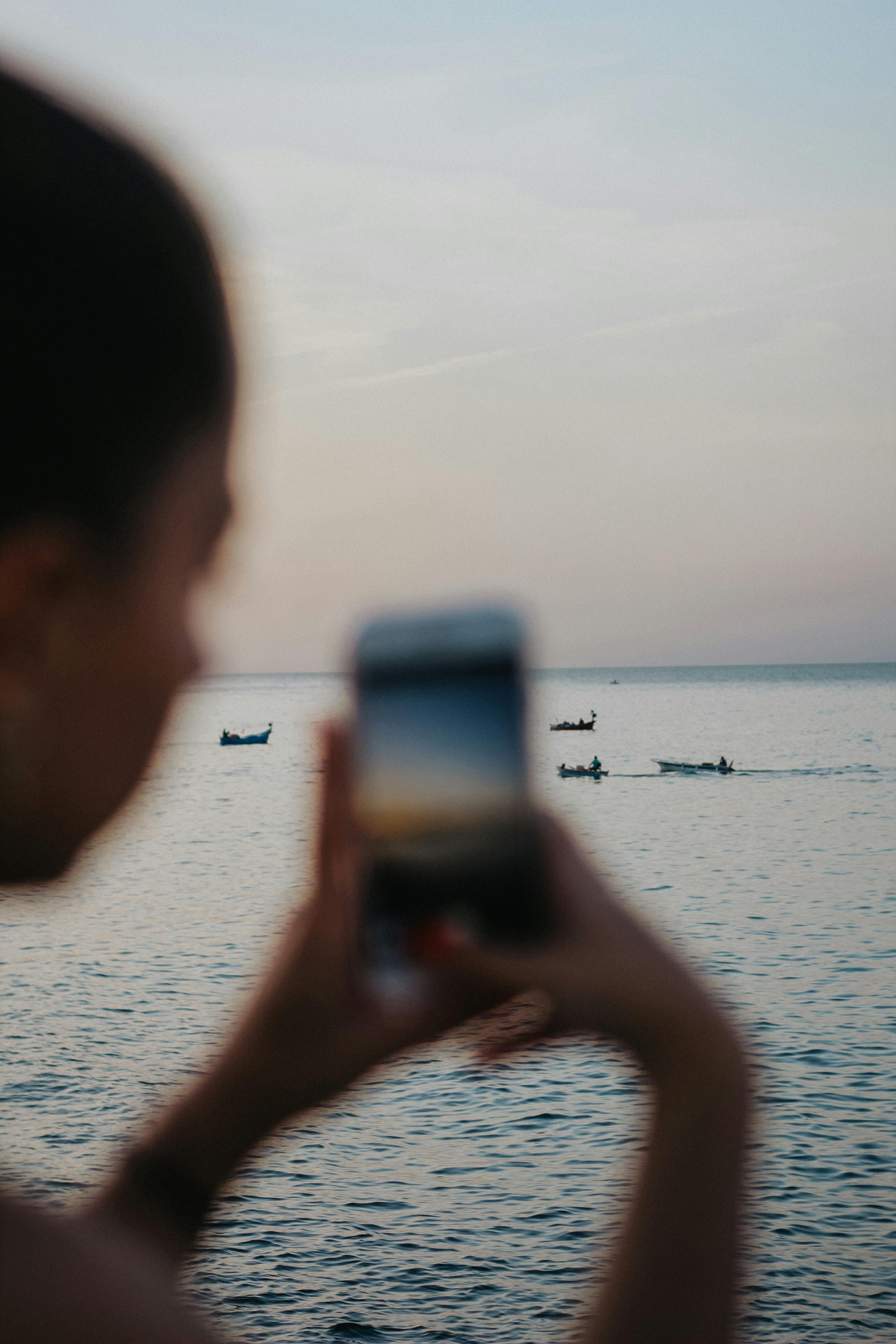 person taking photo of sea on cellphone