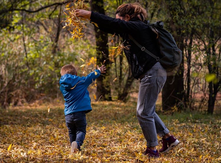 Child And Mother Playing With Autumn Leaves