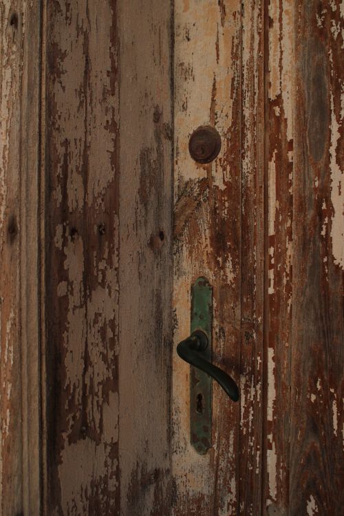 Free A close-up of a rustic, weathered wooden door featuring antique handle and knob. Stock Photo