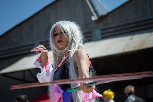 Engaging image of a cosplayer with long white hair posing outdoors in an urban environment.