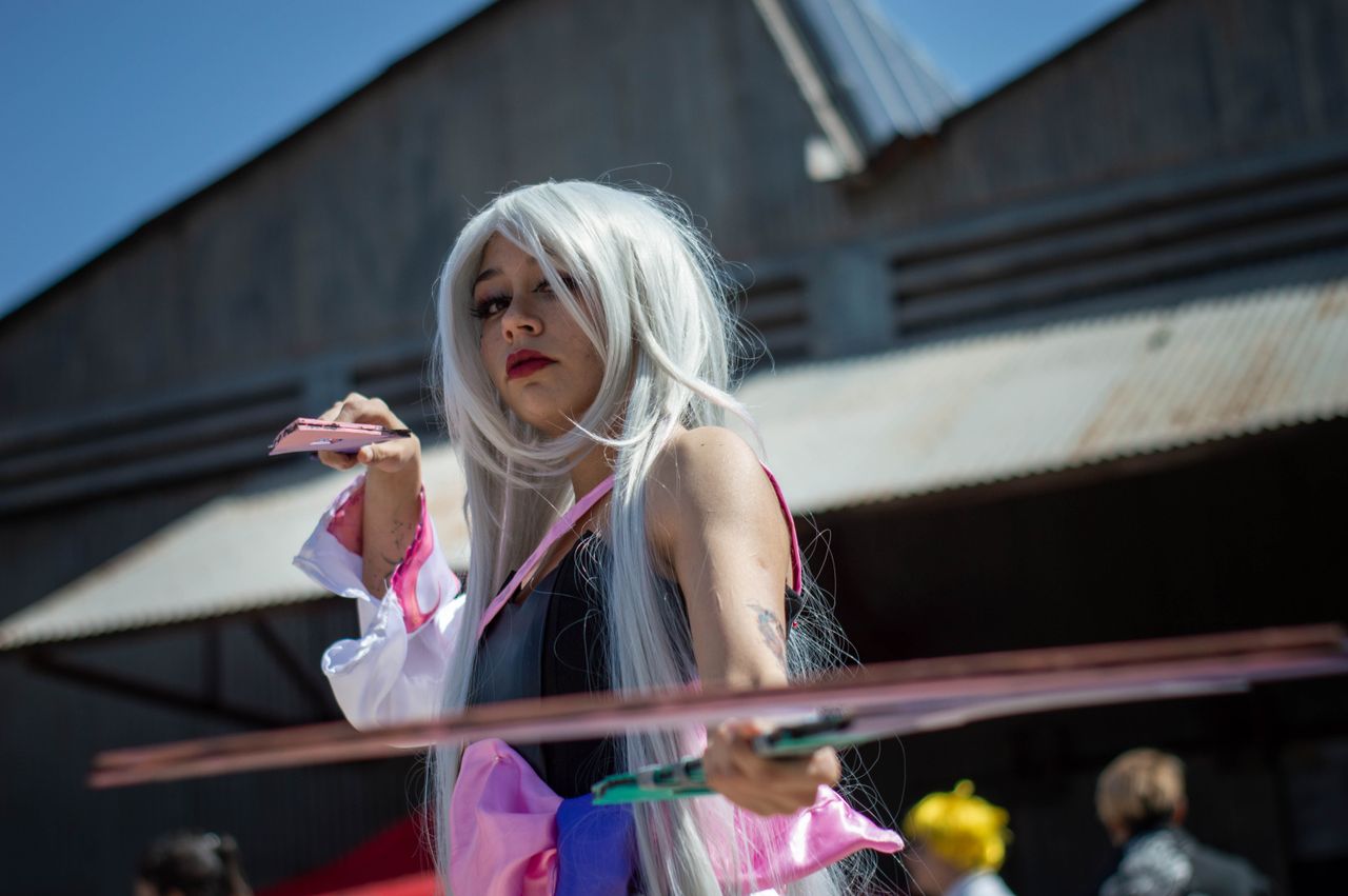 engaging image of a cosplayer with long white hair posing outdoors in