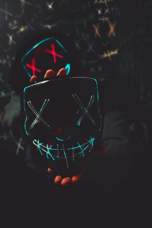 Free A mysterious neon mask with X eyes and a stitched smile, symbolizing rebellion and anonymity. Stock Photo