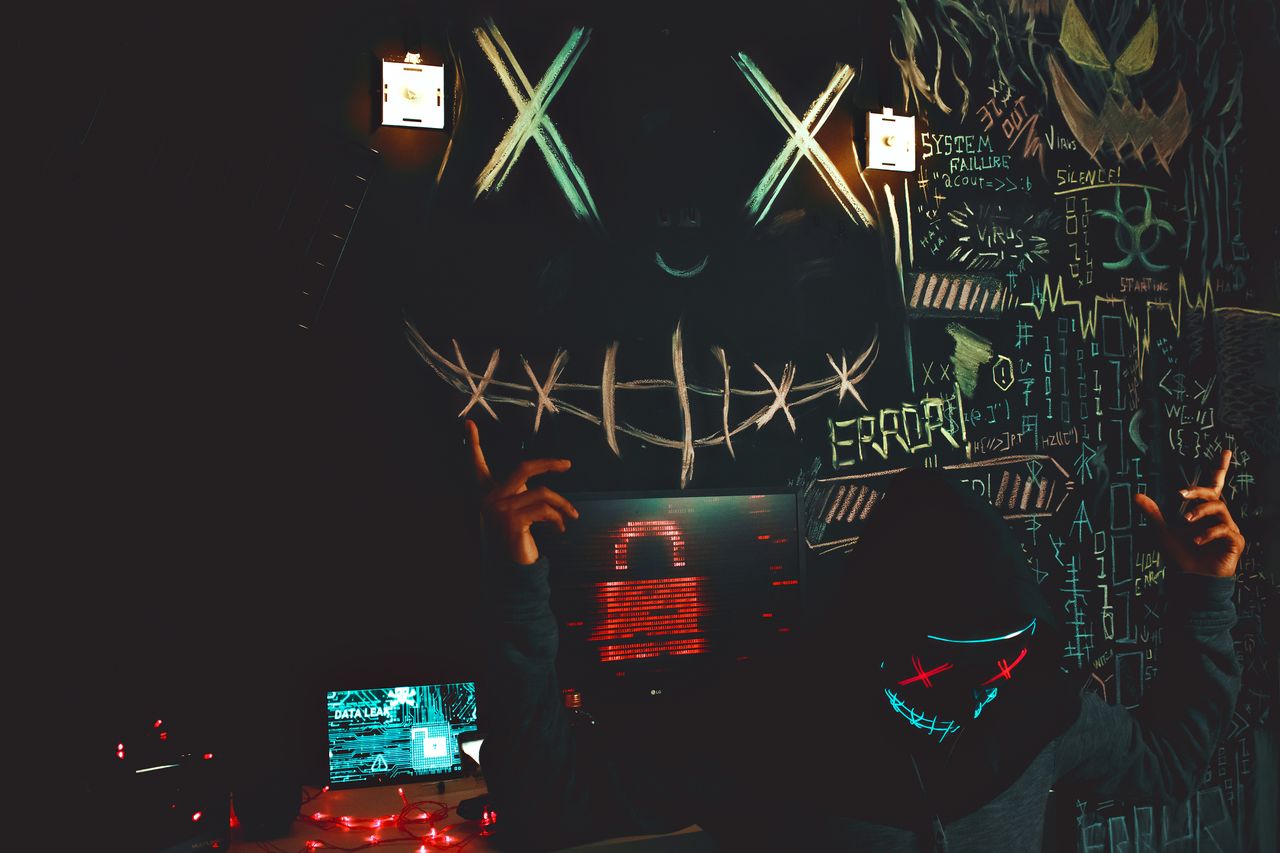a masked individual in a cyberpunk inspired room filled with graffiti