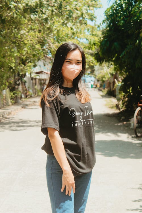 Teenage Girl Standing in Black Shirt and Denim Jeans Wearing Face Mask