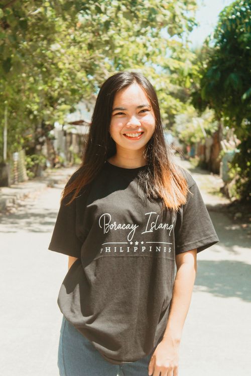 Free Teen girl smiling in a Boracay Island t-shirt on a sunny day outdoors. Stock Photo