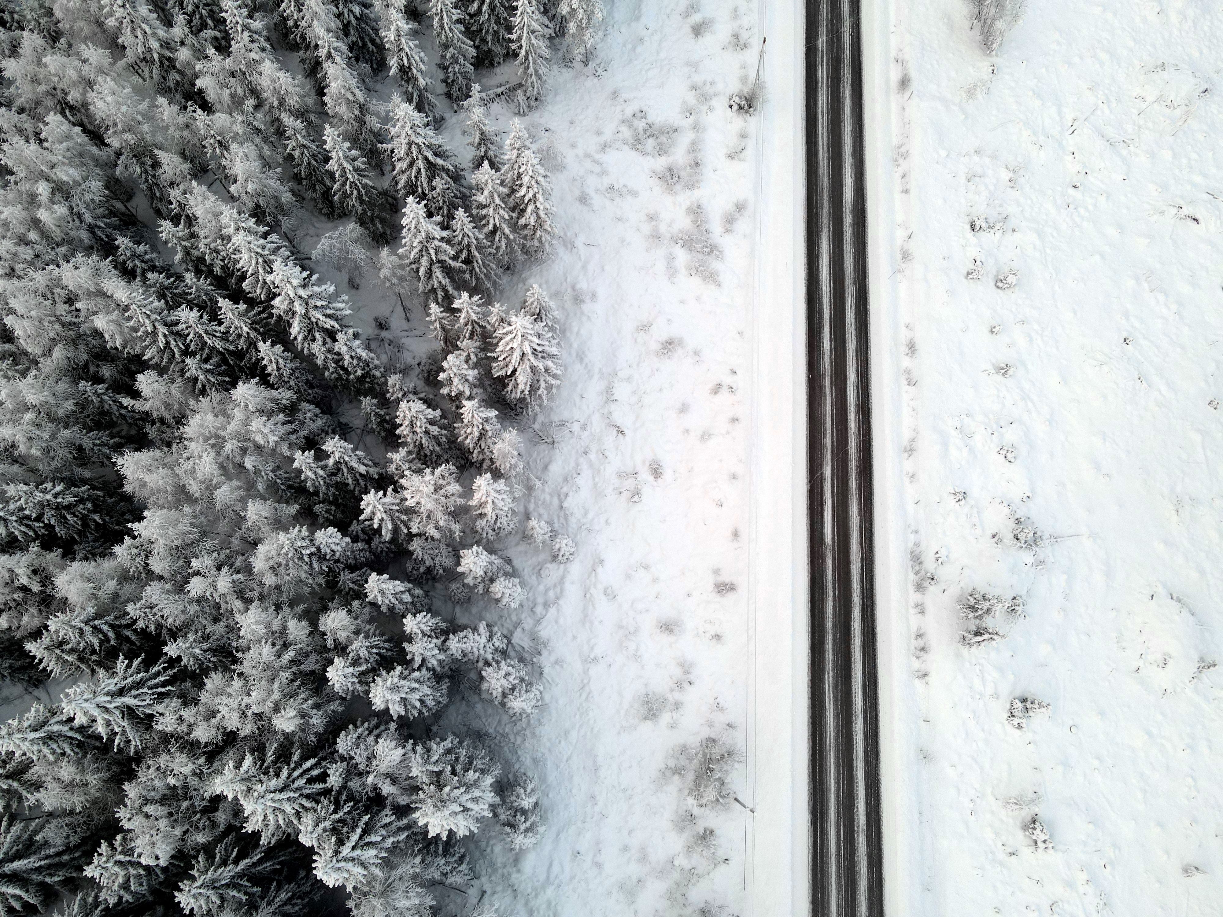 Aerial view of a snow-covered road and forest in Notodden, Norway during winter.