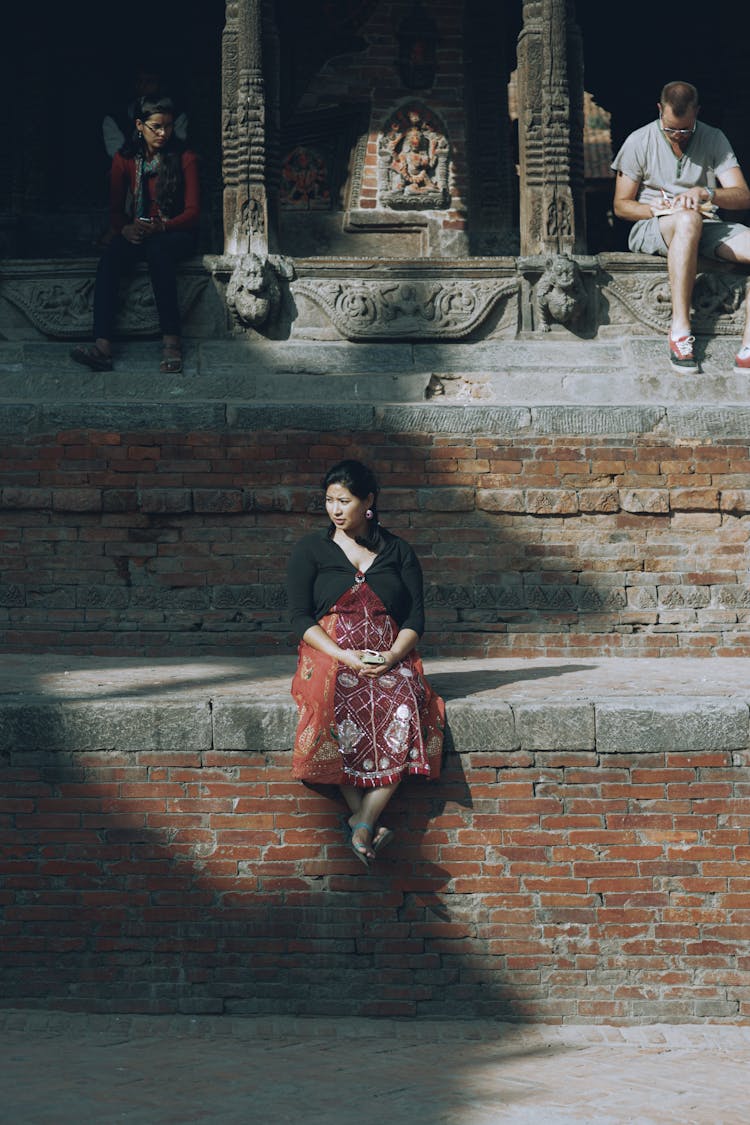 Woman Sitting On Brick Stairs Near Temple