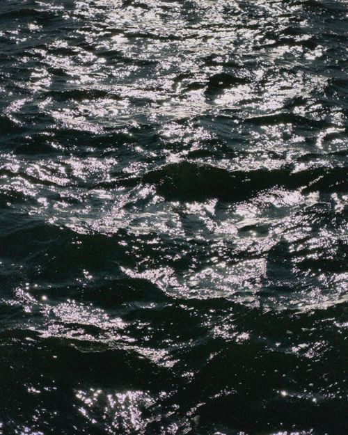 Free Close-up of ocean waves shimmering under sunlight, creating a calming seascape. Stock Photo