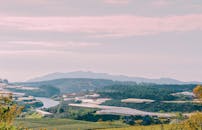 乡村风景如画，多云的天空下，农田、河流和远处的山脉尽收眼底