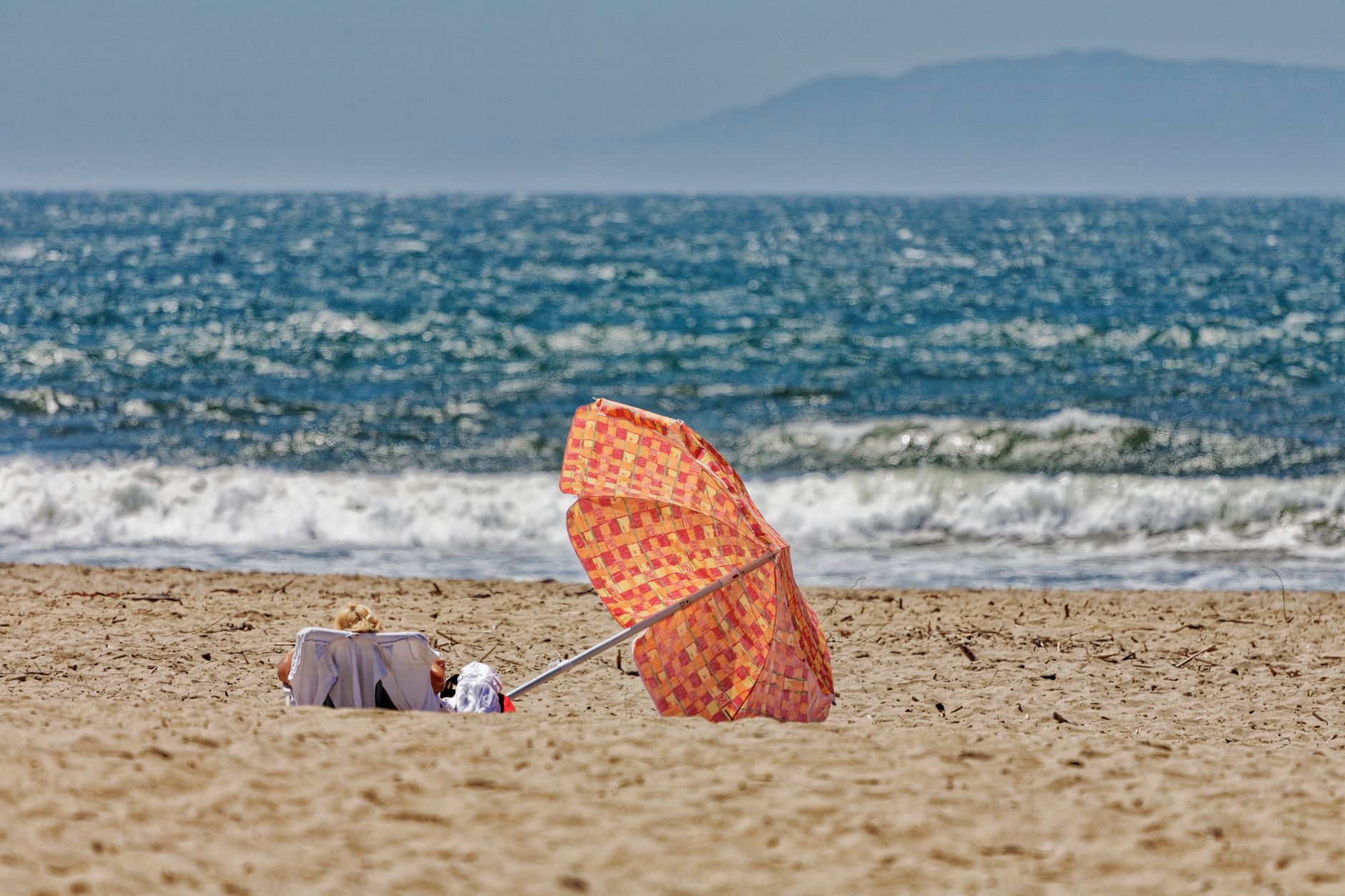 A vibrant beach scene in Ventura, CA with an umbrella and ocean waves.