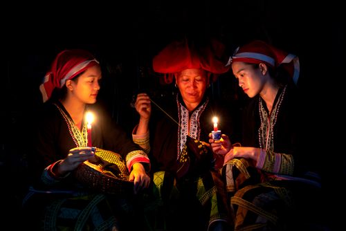 Free Three women in traditional attire sewing by candlelight, showcasing cultural heritage. Stock Photo
