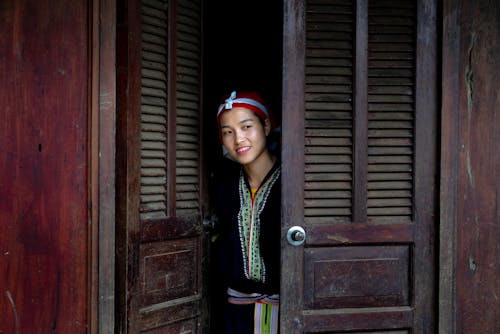 Woman Standing behind the Wooden Door while Wearing Traditional Clothes 