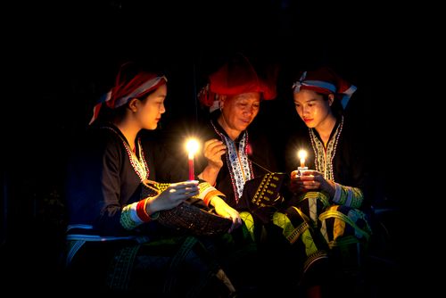 Free Three people in traditional attire gather with candles, creating a warm and intimate atmosphere. Stock Photo