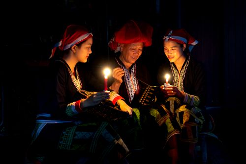 Free A serene scene of three people in traditional attire holding candles, evoking cultural heritage. Stock Photo