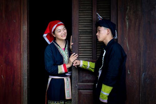 Boy and a Girl Wearing Traditional Clothes Talking in Front of a Building Entrance