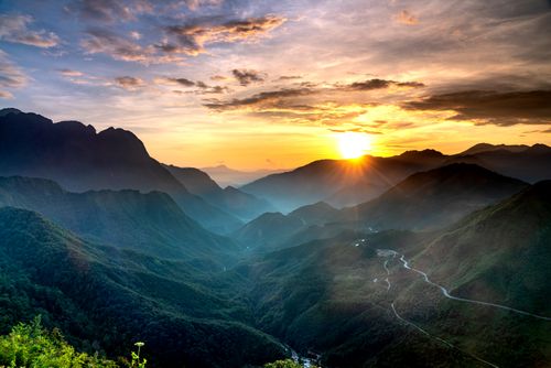 Free Capture of a breathtaking sunrise casting light over a vast mountain range and dramatic sky. Stock Photo