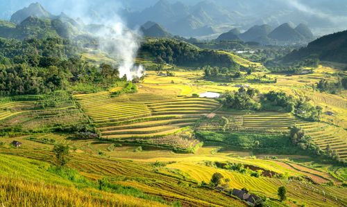 Free A breathtaking aerial view of lush green terraced fields in a picturesque mountain valley during day time. Stock Photo