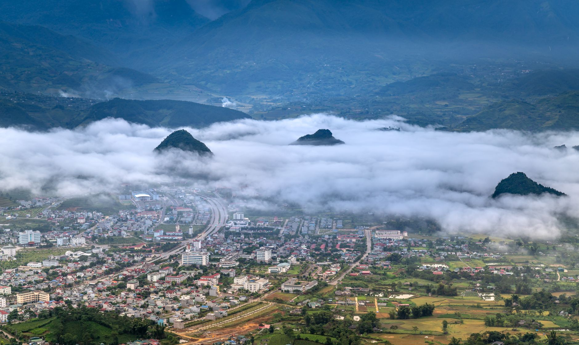 Breathtaking aerial view of Lai Chau City framed by mist-covered mountains at dawn in Vietnam.