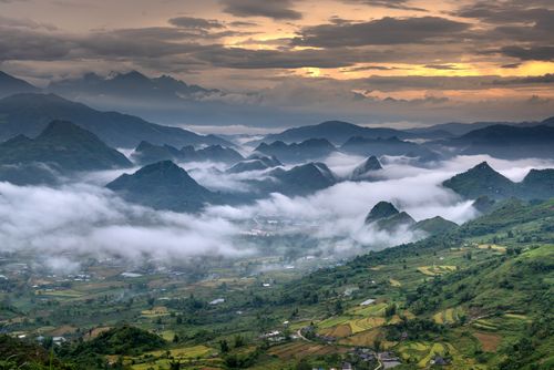 Free A breathtaking view of a fog-covered mountain landscape at sunrise with lush greenery. Stock Photo