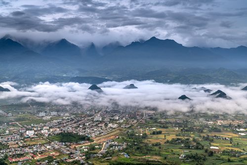 Free A breathtaking view of a city surrounded by mountains and clouds, captured from above. Stock Photo