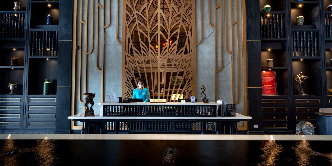 A hotel receptionist at the front desk where guests review charges in 2026