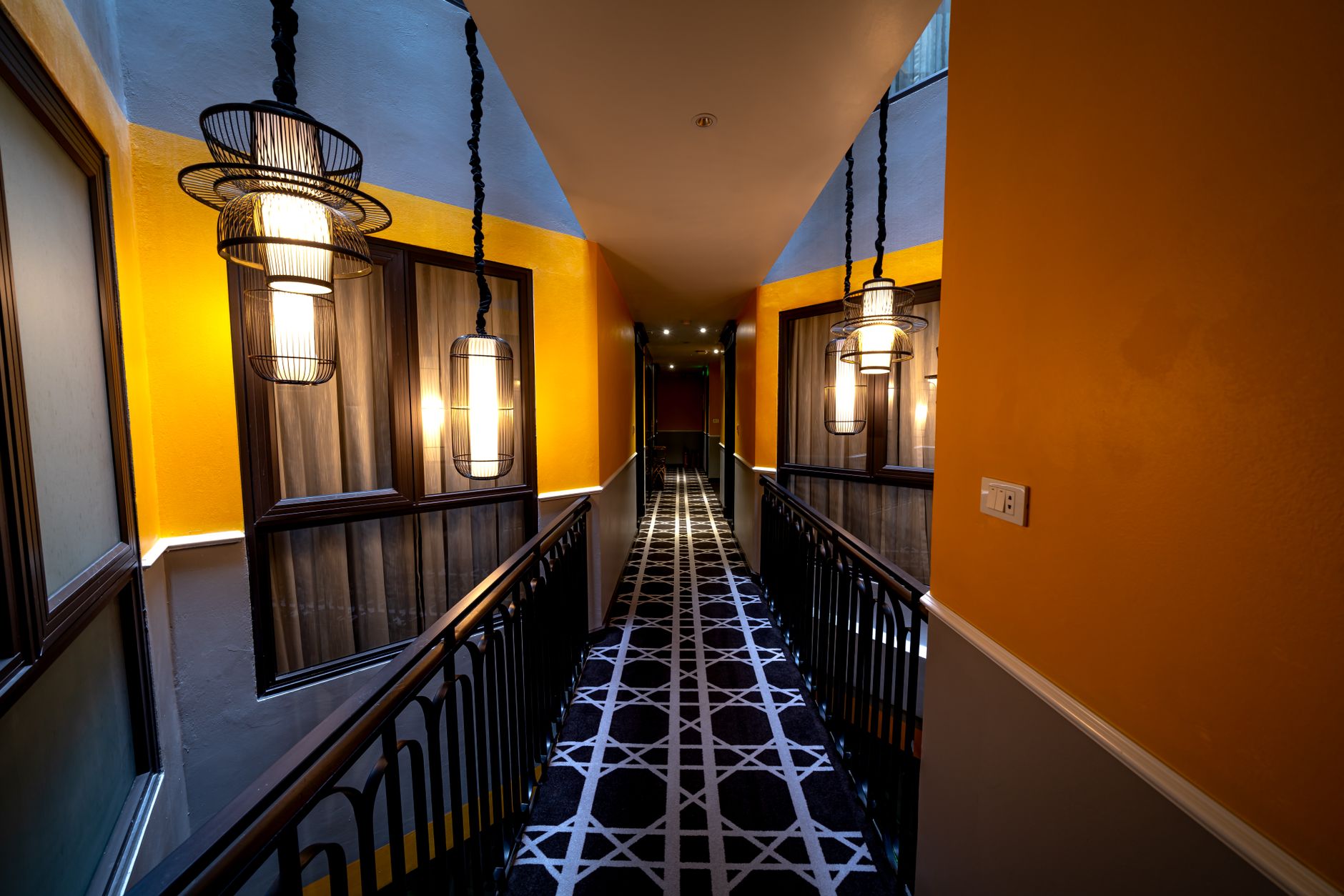 A sleek hotel hallway featuring contemporary design and elegant hanging lamps.
