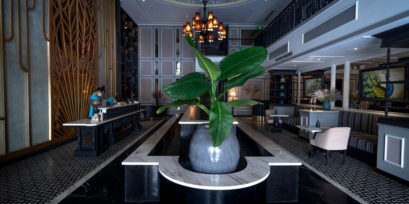 An elegant, high-ceilinged luxury hotel lobby with marble floors