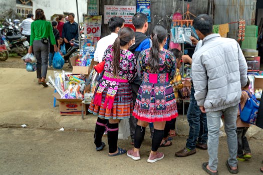 People in vibrant traditional attire shopping at a busy outdoor market.
