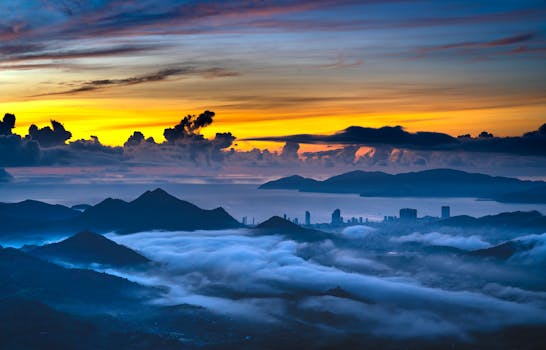 Captivating view of foggy mountains with a city skyline under a dramatic sunset sky.