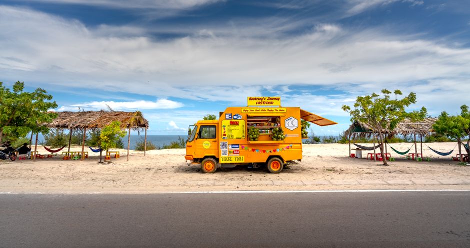 Photo by Quang Nguyen Vinh A colorful food truck parked by the beach offers snacks under tropical skies.