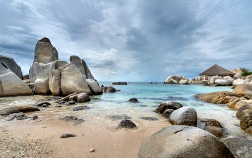 Photo of Beach with Rocky Shore Under Cloudy Sky