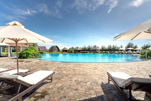 Free White and Brown Wooden Lounge Chairs with Umbrellas on Poolside Stock Photo