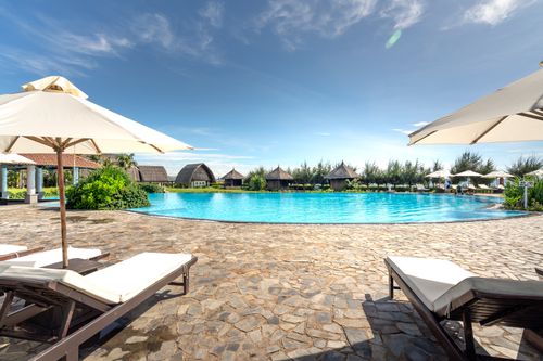 Free Serene poolside view with lounge chairs and umbrellas at a tropical resort, ideal for relaxation. Stock Photo