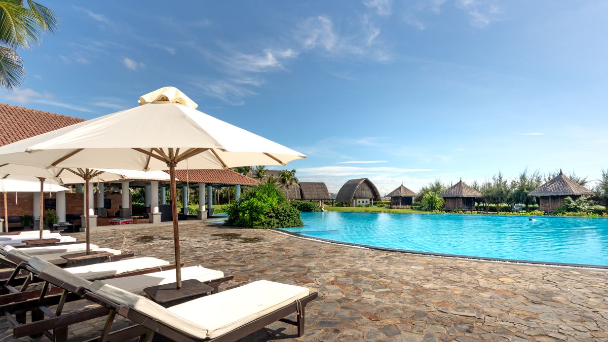 Resort pool lined with sunbeds and umbrellas on a clear summer day