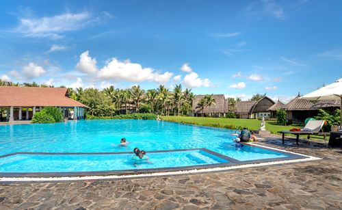 Free Luxurious tropical resort featuring a vibrant swimming pool under sunny skies, ideal for summer vacations. Stock Photo