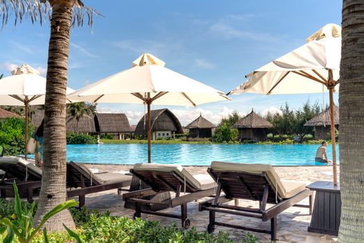 Relax by the pool with luxury resort amenities under sunny skies.