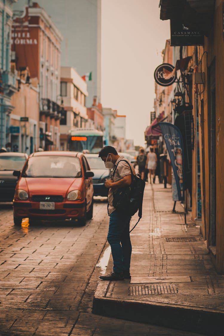 Man In Face Mask On Sidewalk In City Street