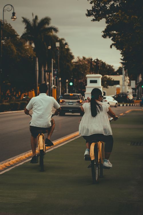 Free Man and woman biking on a city road, enjoying an outdoor summer day. Stock Photo