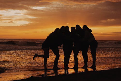 Women Hugging on Sea Shore at Sunset