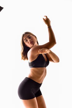 Stylish woman striking a pose in black sportswear during a studio photoshoot with white backdrop.